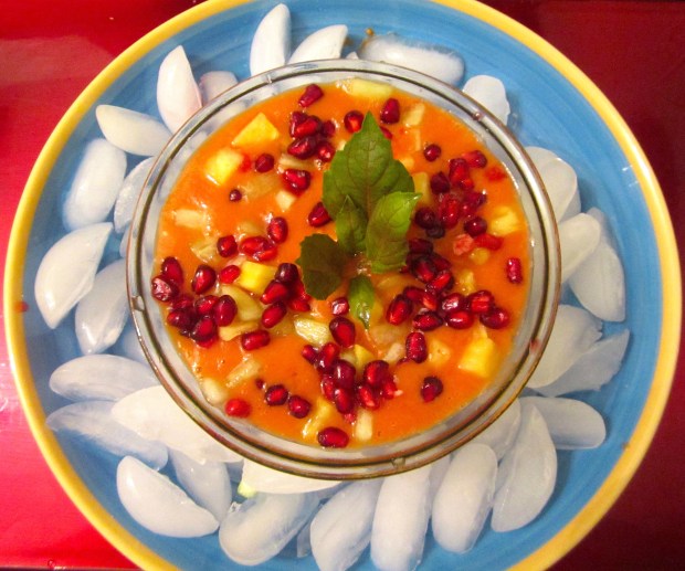 ladle iced tomato soup on top of fruit, sprinkle more fruit, garnish with opal basil